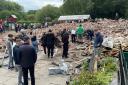 People inspect the rubble remains as they gather at The Crooked House pub in Himley, near Dudley