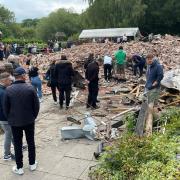 People inspect the rubble remains as they gather at The Crooked House pub in Himley, near Dudley